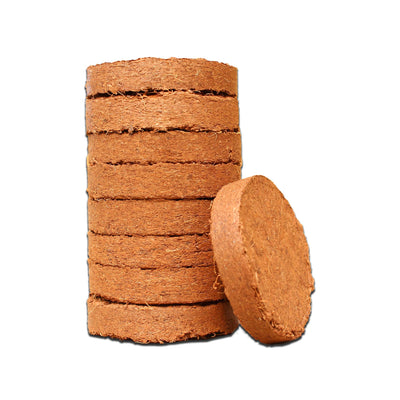 A stack of 8 50mm coco coir discs. A ninth disc is on its side in front of the stack. 